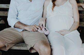 Man and pregnant wife sitting on bench.