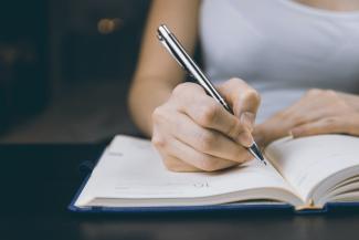 Woman writing in a paper planner with a pen